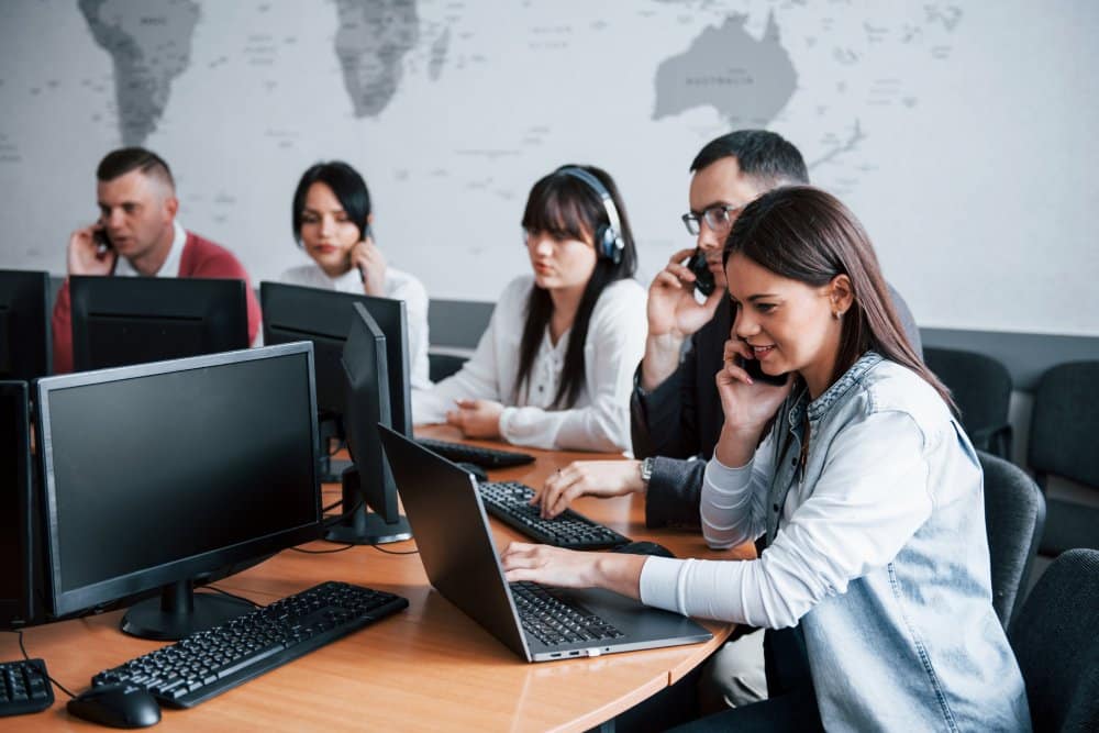 Pessoas mexendo em computadores e notebooks adquiridos através do outsourcing de ti em uma mesa